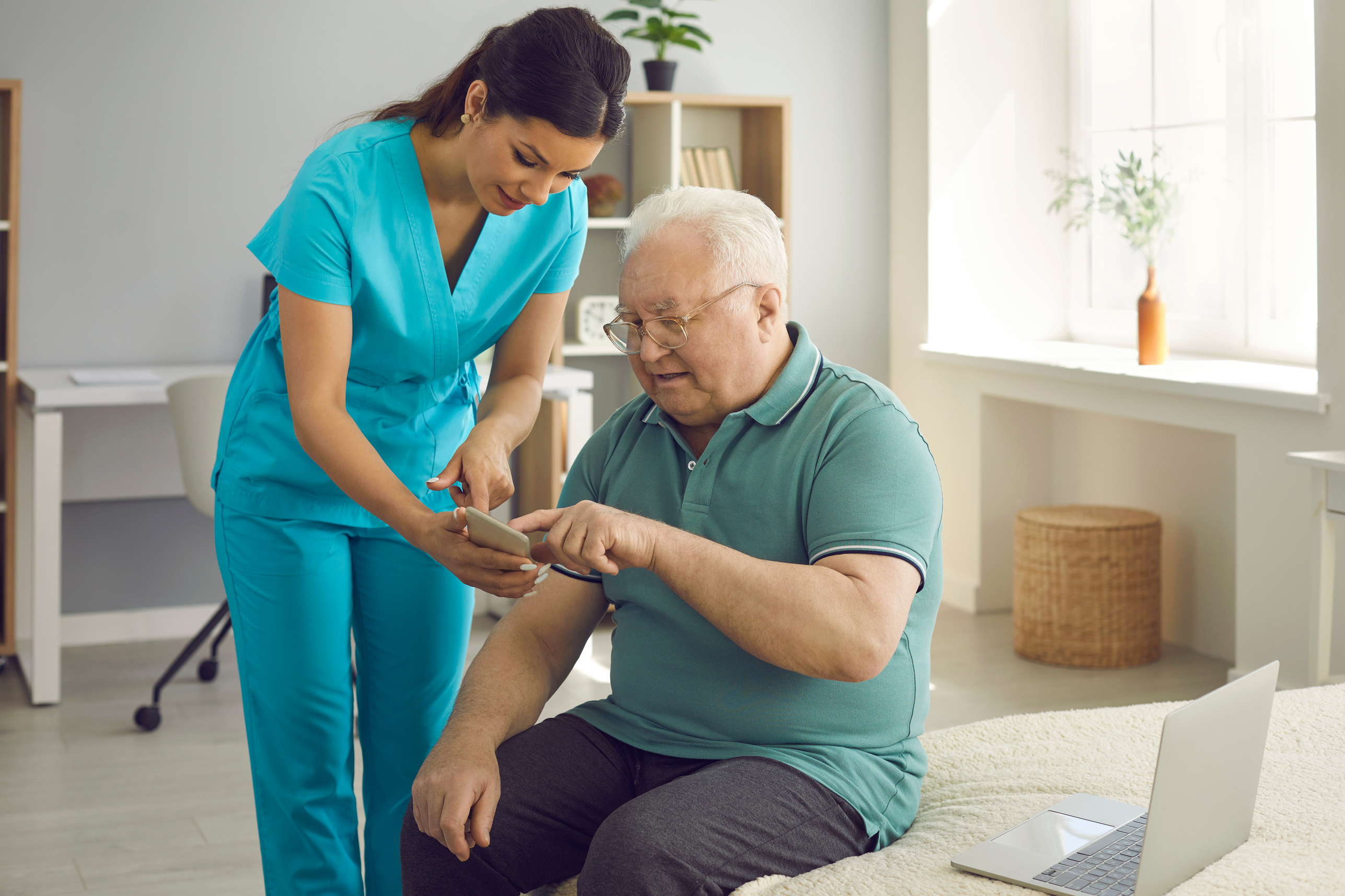 Healthcare Worker Teaching Her Senior Patient to Use Health App on His Mobile Phone